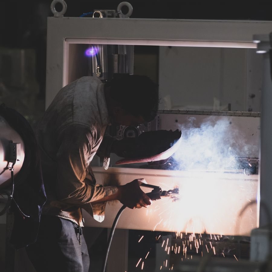 Welder working on a metal machine casing